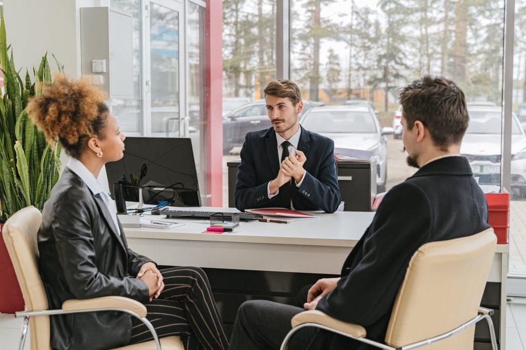 man in a suit talking with a couple in an office